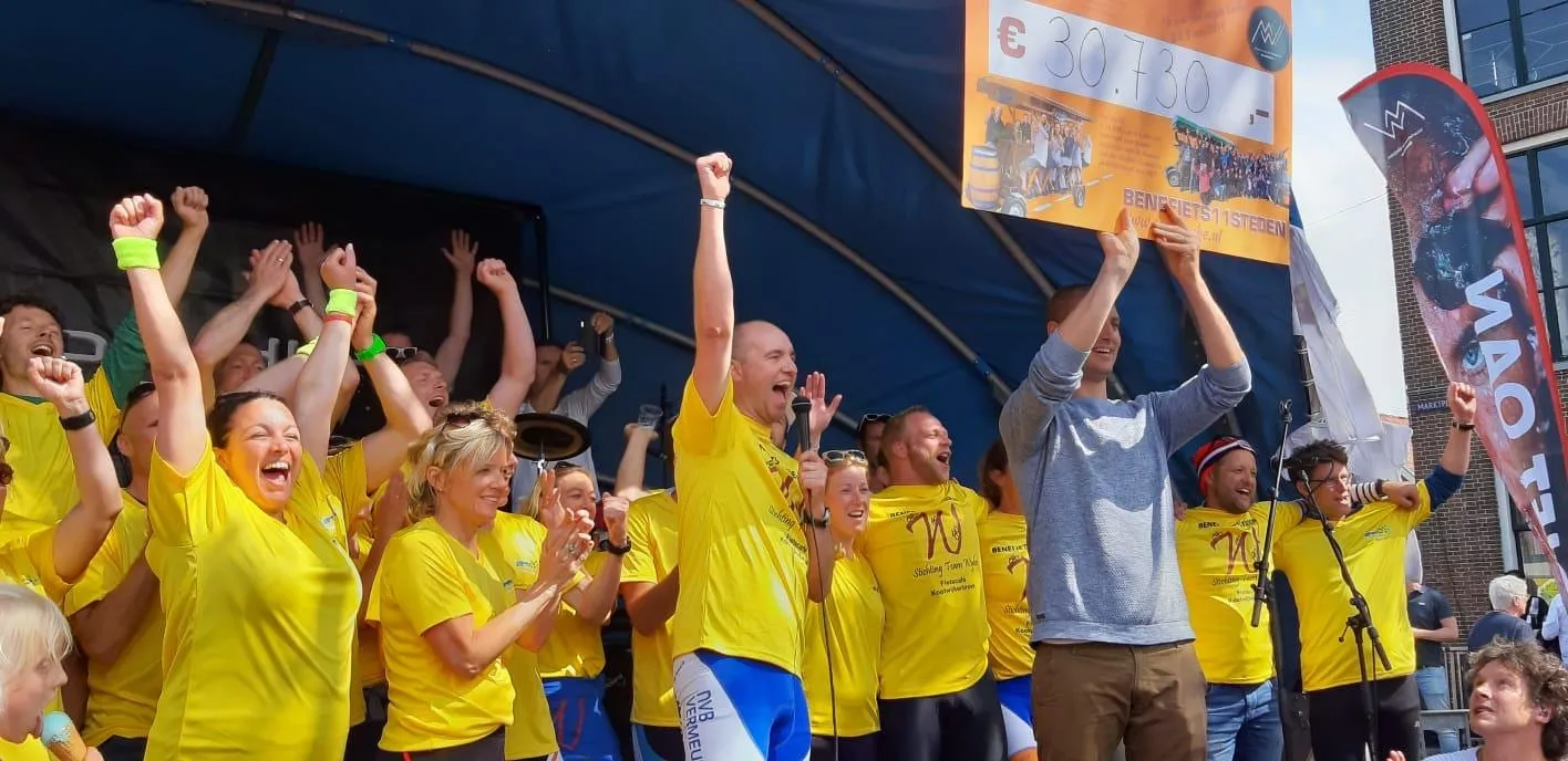 Team Wybe in gele shirts juicht met de cheque van de eerste actie in 2014